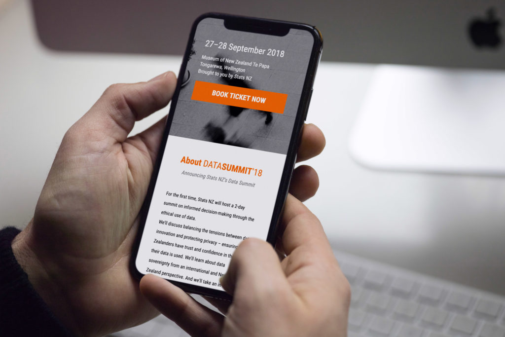 data-summit-web-1 Hand holding a mobile phone showing a mobile optimised conference website by Wonderlab.