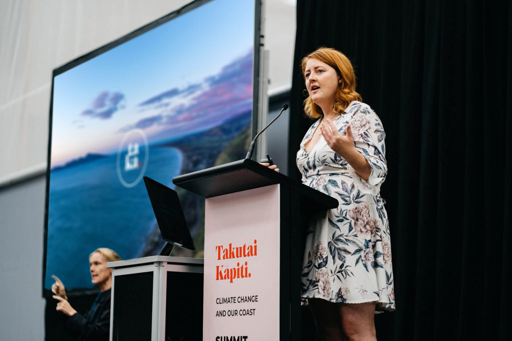 DSC01898_summit-speaker Women speaking with a background display board and plinth design by brand agency Wonderlab