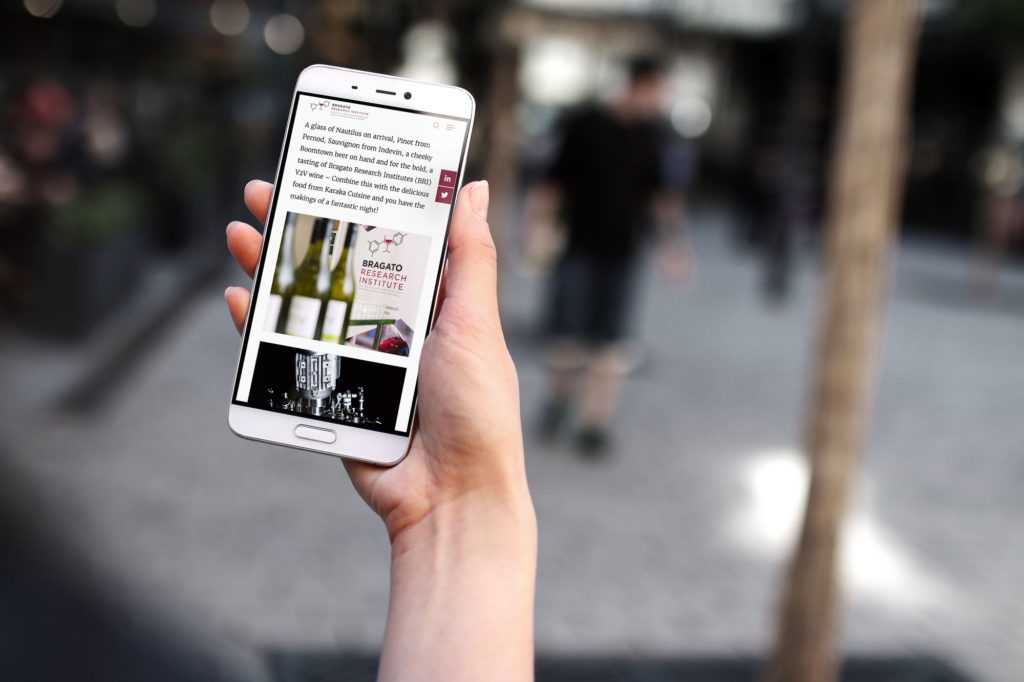 bragato-web-mobile-1 Hand holding a mobile phone showing a mobile optimised website by Wonderlab.