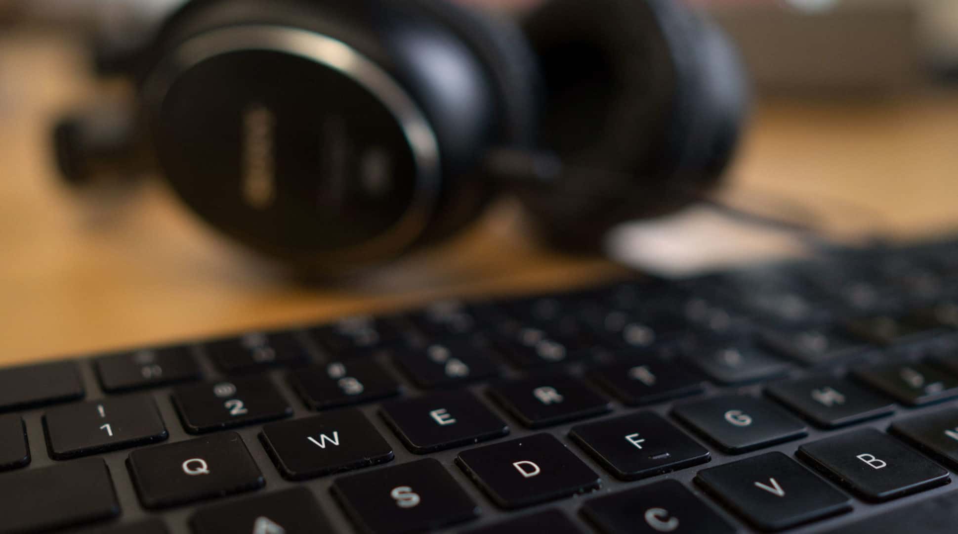A close up of a keyboard with headphones on it.