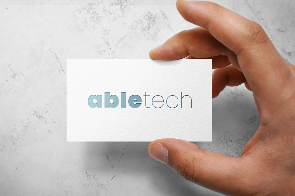 Artboard 1 copy 3 A person holding up a business card with the word abletech on it.