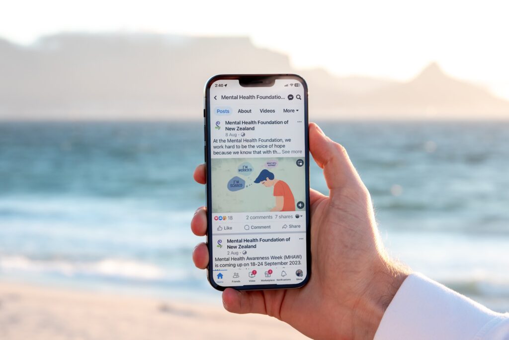 MHF-iPhone Mockup _1-0 A man is holding up a phone with a social media app on it.