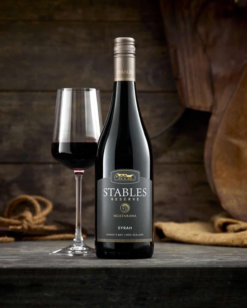 Web-Stables-Reserve-Syrah-Tile A bottle of Stables red wine and a glass on a wooden table.
