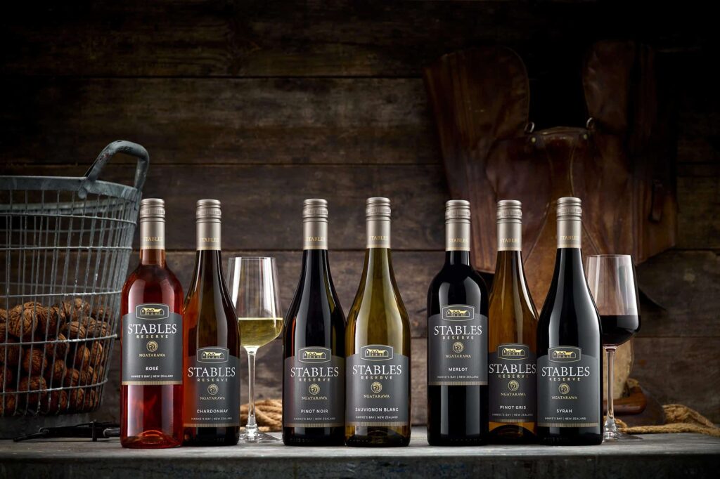 stables-res-range-NV-web A group of wine bottles and glasses on a wooden table.