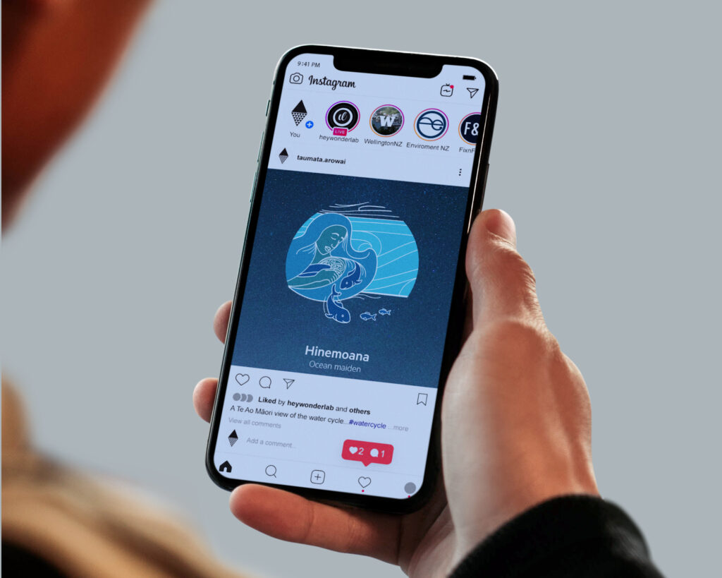 TA_watercycle_hinemoana-mobile A person holding an iphone with an image of a whale on it.