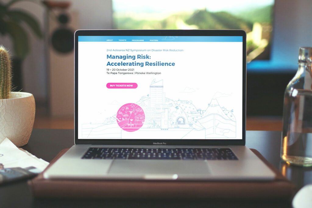 eqc-conf-website A laptop sits on a table next to a plant and a coffee cup.