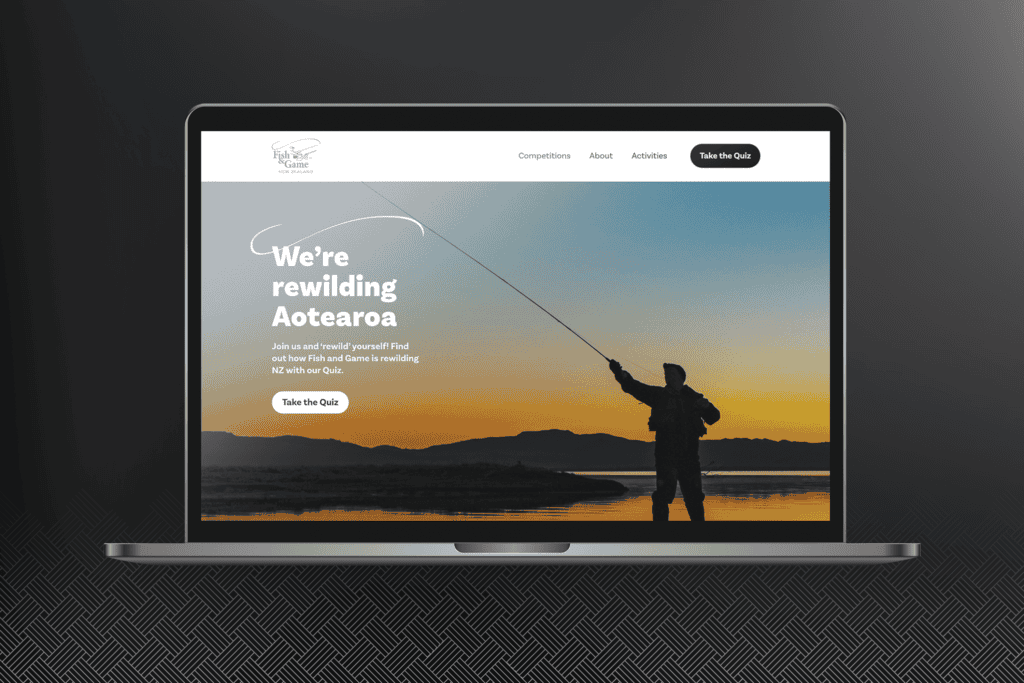 Fish-and-Game_ReWild-Portfolio-Mockups_Laptop A laptop displays a website with a headline "We're rewilding Aotearoa" and an image of a person fishing at dusk. The website has menus for Competitions, About, and Activities.