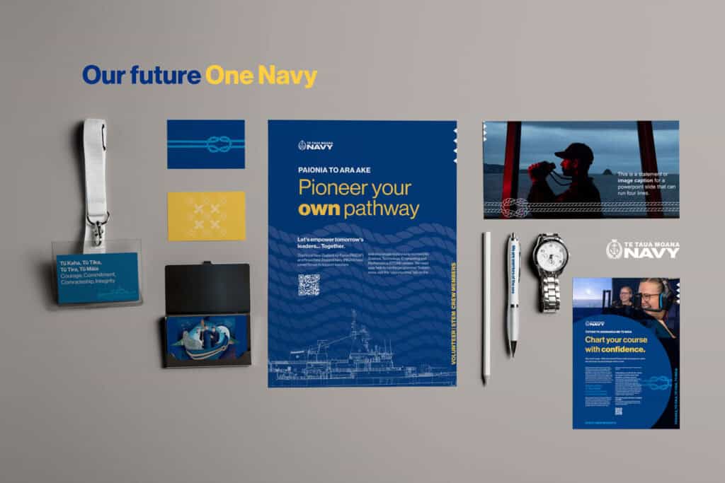 NZ-Navy-brand-items-flat An arrangement of navy comms materials includes brochures, ID cards, a pen, a watch, and a lanyard. The central brochure emphasizes "Pioneer your own pathway" with navy imagery and logo. The overall theme promotes confidence and pathways in the Navy.