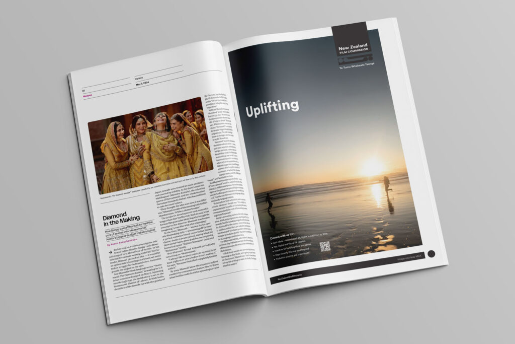 Cannes-Variety-advert-NZFilmCommission2 An open magazine displaying two pages. The left page features an article with an image of people in traditional attire. The right page is an advertisement with the text "Uplifting" over a serene beach sunset scene, showing silhouettes of people by the water.